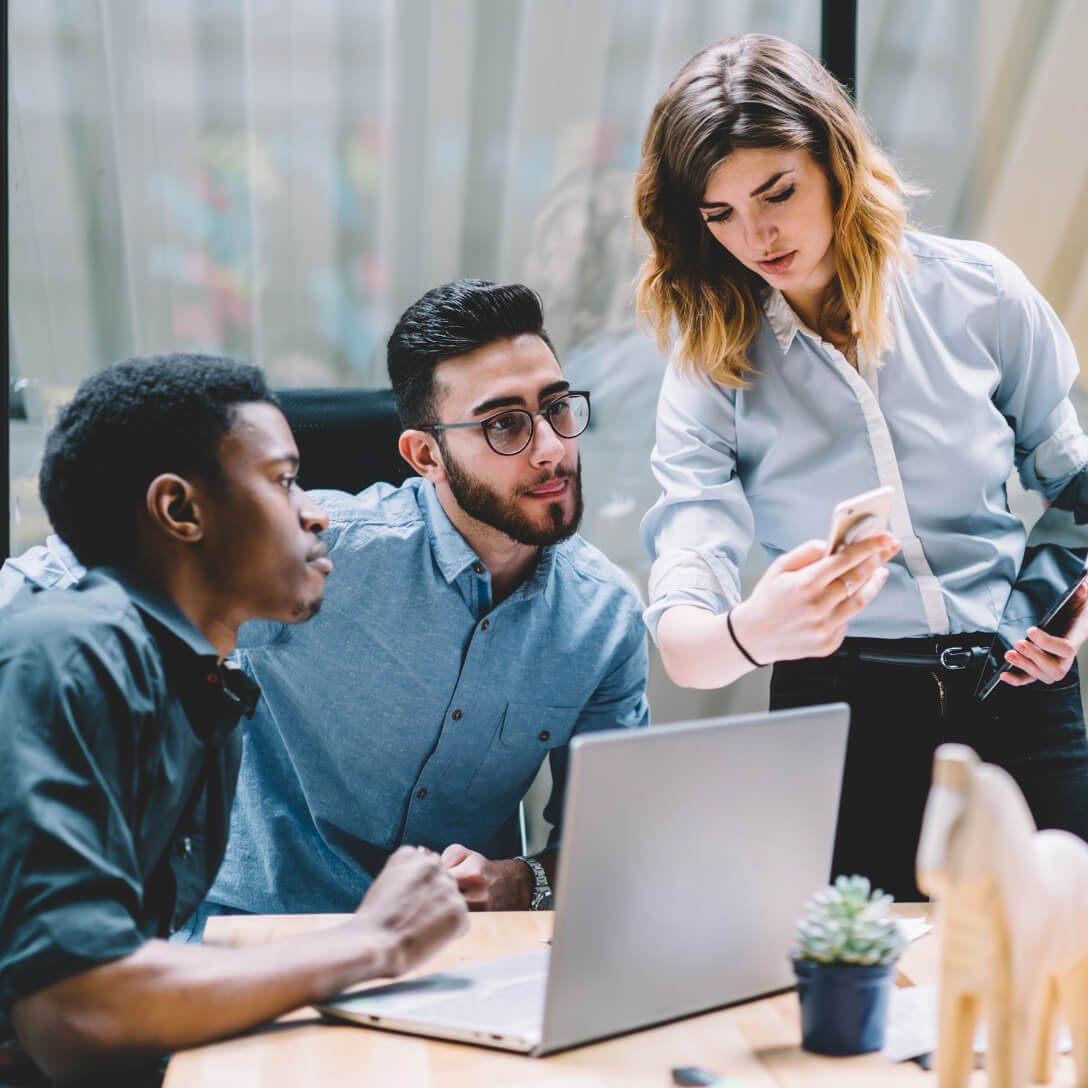 Group of young professionals gathered around a computer