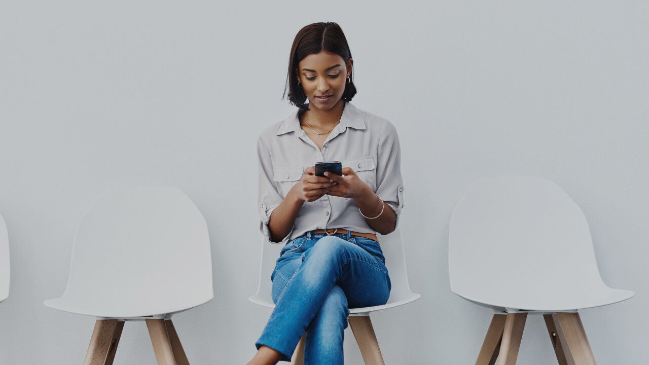 Young woman sitting in a chair looking at her cell phone