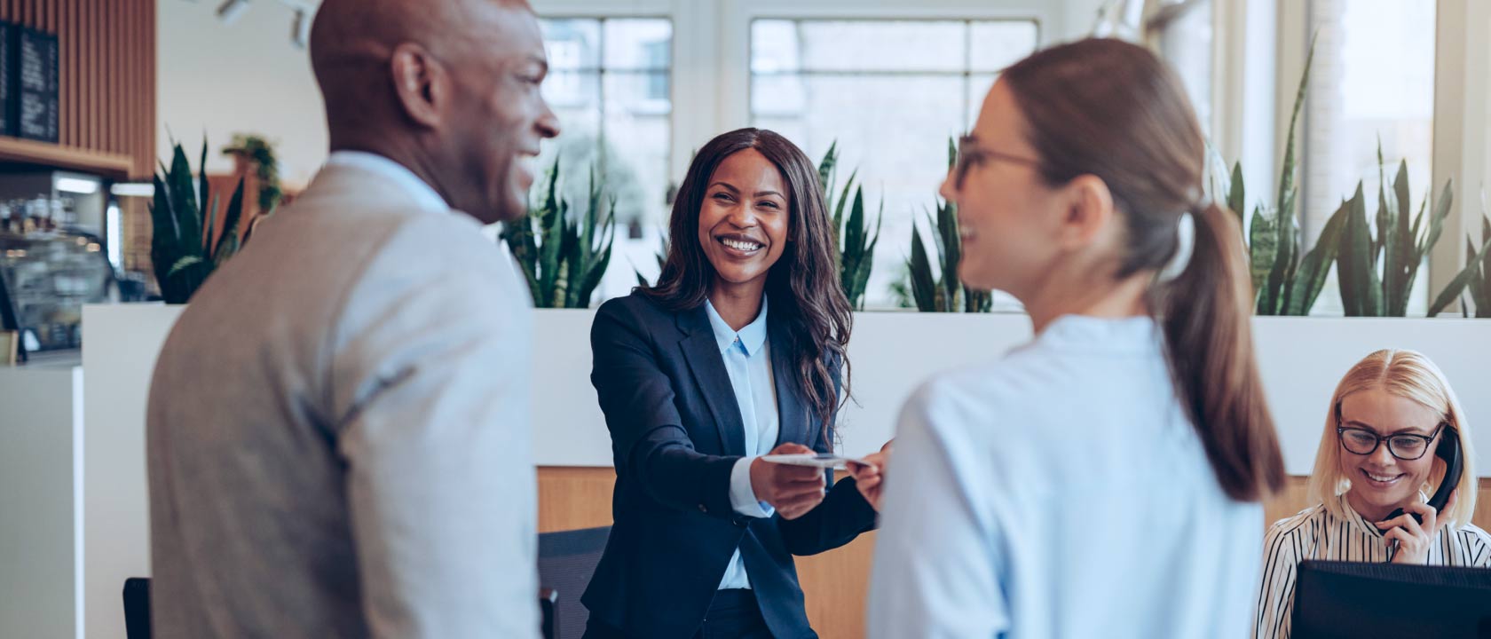 Photo of two people checking into a hotel with the manager or front desk representative handing them a card